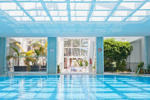 Innenpool des El Mouradi Club Kantaoui mit blauen Wänden und Pflanzen im Hintergrund.
