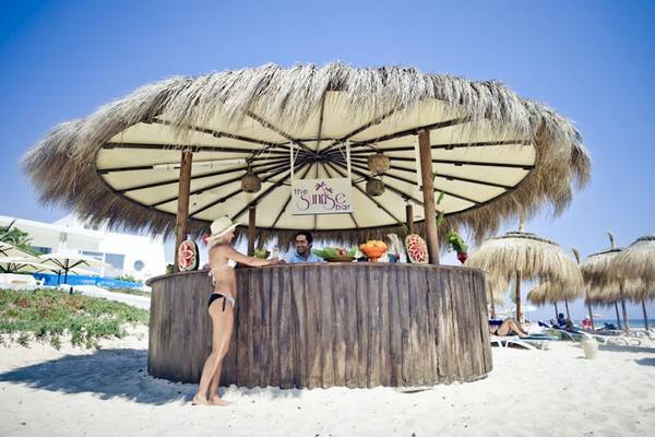 Strandbar mit Frau in Bikini und Hut, Mann hinter der Theke