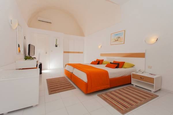 Innenansicht eines Schlafzimmers im El Mouradi Club Kantaoui Hotel mit einem Bett, Nachttischen und einer weißen Inneneinrichtung.