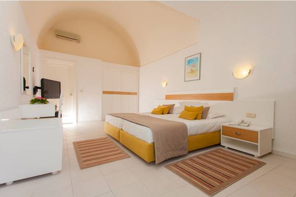 Hotelzimmer im El Mouradi Club Kantaoui mit Doppelbett, gelben Kissen und modernen Möbeln.