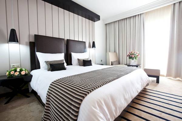 Ein elegantes Hotelzimmer im El Mouradi Palace mit einem Doppelbett, Blumenvase, und modernen Möbeln.