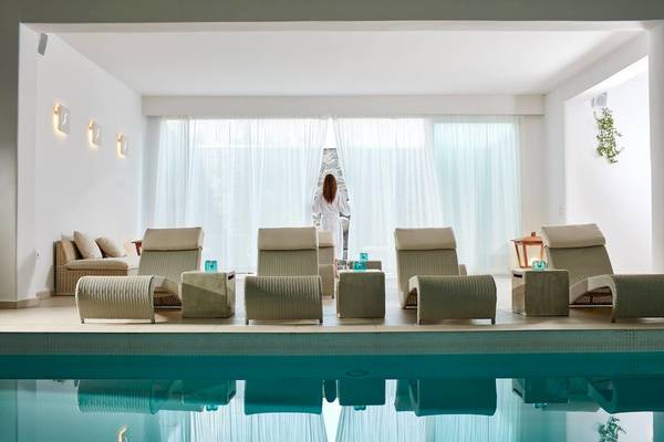 Lounge-Bereich am Pool im Aegean Plaza Hotel mit weißen Möbeln und großen Fenstern.