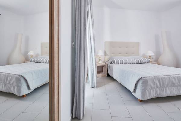 Zwei Schlafzimmer im Aegean Plaza Hotel mit weißen Möbeln und grauen Vorhängen.