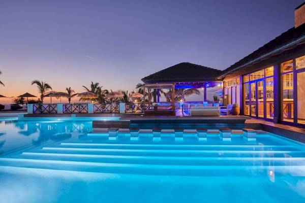 Abendlicher Swimmingpool im Secrets Lanzarote Resort & Spa mit blauer Beleuchtung und umliegenden Palmen.
