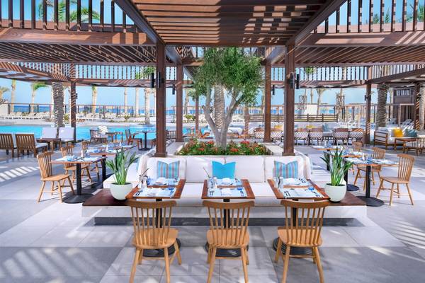 Überdachte Terrasse im Iberotel Costa Mares Hotel mit Tischen und Stühlen, Blick auf einen Pool und Palmen.