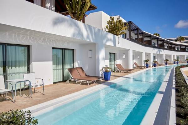 Außenpool des Secrets Lanzarote Resort & Spa mit Lounge-Liegen und Tischen.