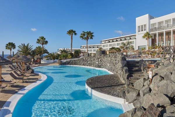 Außenpoolbereich des Secrets Lanzarote Resort & Spa mit weißen Liegen und Palmen