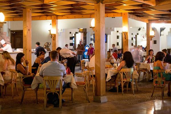 Innenbereich des Restaurants im Sharm Resort mit Gästen an Tischen und einem Koch in der Küche.