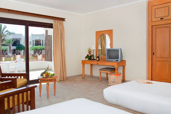 Hotelzimmer im Sharm Resort mit Balkon, Fernseher, Tisch und Stühle.