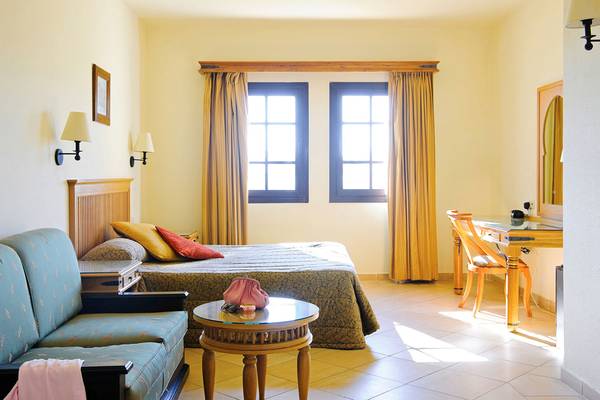 Hotelzimmer im Sharm Resort mit Bett, Sofa, Tisch und Fenstern.