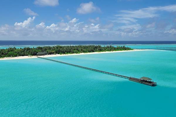Außenansicht des Holiday Island Resort & Spa mit Brücke und Insel im türkisfarbenen Wasser.