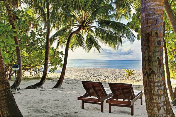 Zwei Liegen auf dem Strand des Holiday Island Resort & Spa mit Blick auf das Meer.