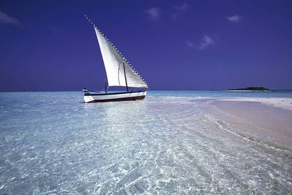 Segelboot im kristallklaren Wasser vor einer Insel