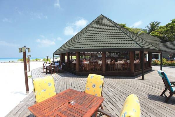 Terrasse des Holiday Island Resort & Spa mit Tischen und Stühlen und Blick auf das Meer.