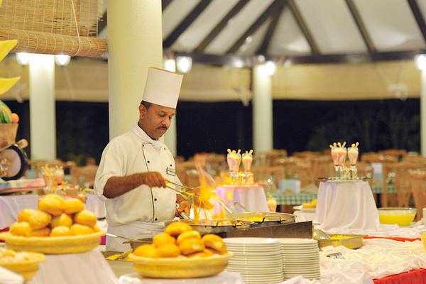Koch beim Holiday Island Resort & Spa beim Anrichten von Speisen auf einem Buffet.