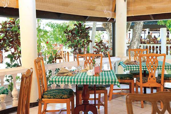 Innenansicht des Restaurants im Holiday Island Resort & Spa mit grünen Tischdecken und Holzstühlen.
