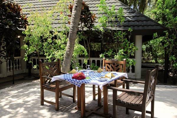 Holztisch im Garten des Holiday Island Resort & Spa mit Tischdecke und Blumen