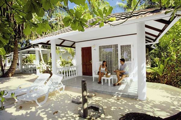 Paar sitzt auf der Terrasse eines weißen Bungalows im Holiday Island Resort & Spa.