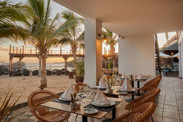 Außenbereich des Secrets Lanzarote Resort & Spa mit Tischen und Stühlen am Strand.