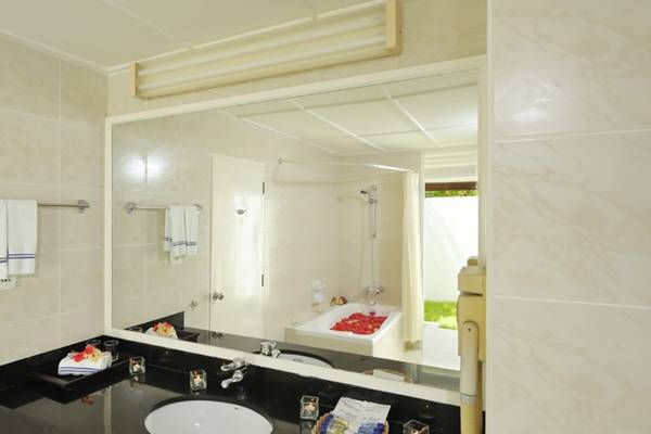Badezimmer im Holiday Island Resort & Spa mit Spiegel, schwarzem Waschtisch und roten Blumen