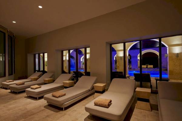 Loungebereich im Secrets Lanzarote Resort & Spa mit weißen Liegen und blau beleuchteten Fenstern.