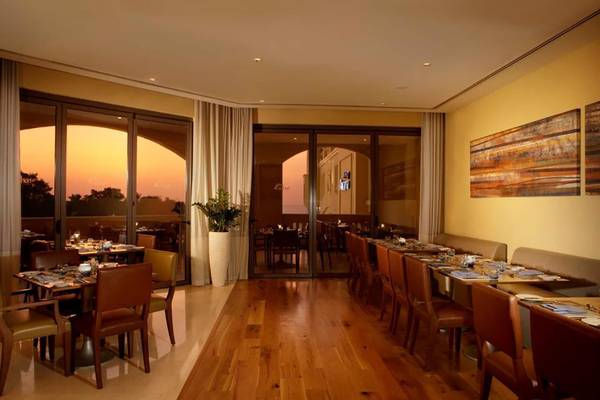Innenansicht des Amwaj Rotana Hotel Restaurants mit Holzboden und großen Glastüren.