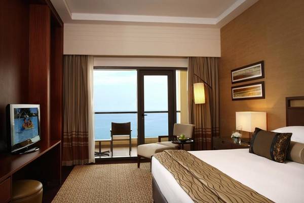 Zimmer im Amwaj Rotana Hotel mit Meerblick, Fernseher, Schreibtisch und Balkon.