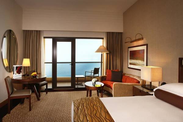 Hotelzimmer im Amwaj Rotana mit Meerblick, luxuriöse Einrichtung und großem Bett.