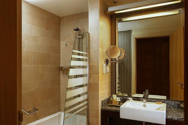 Badezimmer im Amwaj Rotana Hotel mit Badewanne, Glasdusche und Waschbecken
