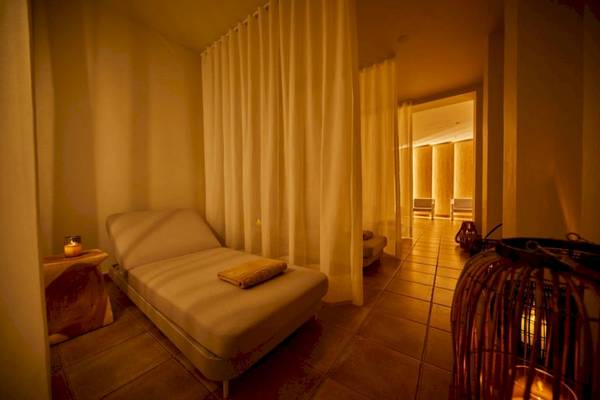 Hotel-Lounge-Bereich im Secrets Lanzarote Resort & Spa mit einem Liegestuhl, Kerzen und einem offenen Durchgang.