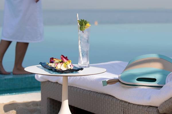 Person am Strand neben einem Tisch mit einem Getränk und einem Tablett mit Essen, Blick auf das Meer, Burj Al Arab Jumeirah