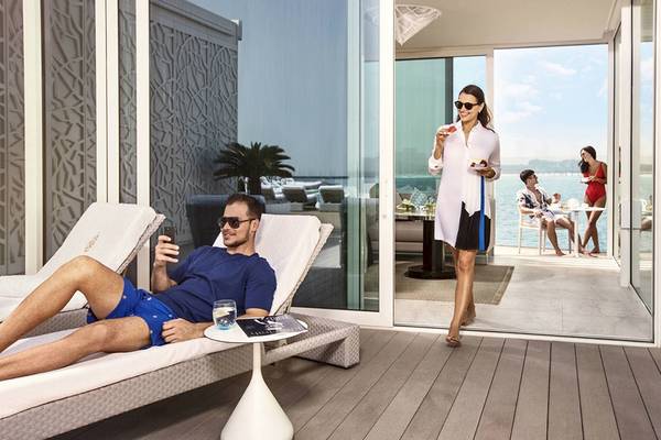 Ein Mann liegt auf einem Liegestuhl und eine Frau steht auf der Terrasse des Burj Al Arab Jumeirah.