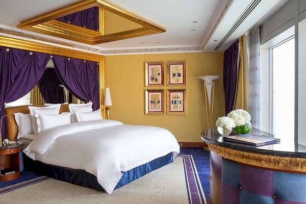Schlafzimmer im Burj Al Arab Jumeirah Hotel mit goldenen Akzenten und violetten Vorhängen.