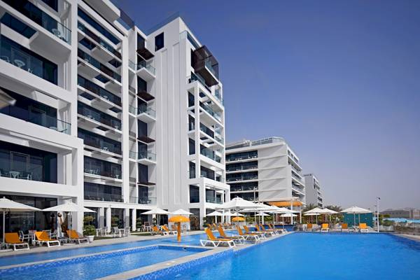 Außenpoolbereich des C Central Hotel & Resort The Palm mit Sonnenliegen und Sonnenschirmen.