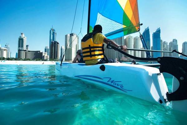 Ein Mann segelt auf einem Katamaran vor der Stadt Dubai.