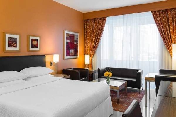 Vier-Punkte-Hotelzimmer in Bur Dubai mit zwei Einzelbetten, Kissen, Dekor und Sofa.