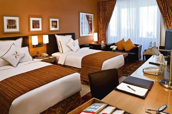 Zwei Doppelbetten mit braunen und weißen Bettdecken in einem Hotelzimmer des Four Points by Sheraton Bur Dubai.