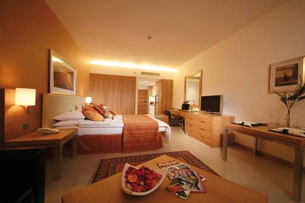 Ein modernes Hotelzimmer mit einem Bett, Tisch, Fernseher und Dekor in der Four Points by Sheraton Bur Dubai.