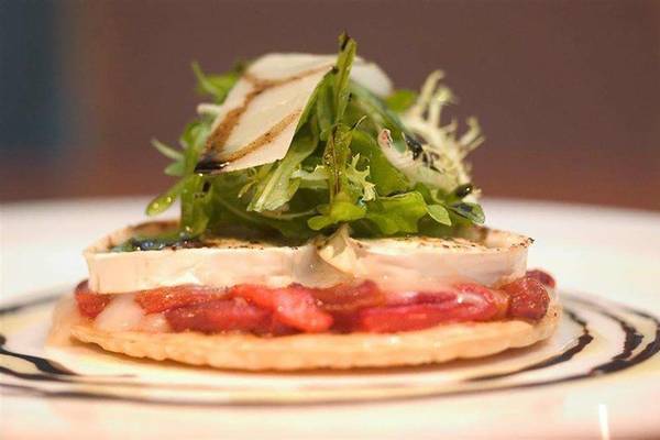 Nahaufnahme eines Tellergerichts mit einem Stück Käse, Tomaten und Salat.