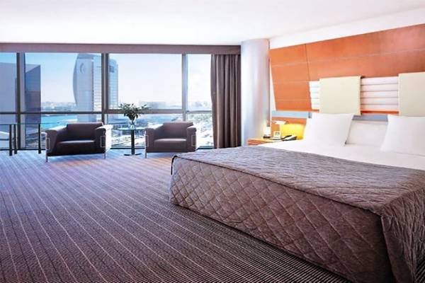 Hotelzimmer im Golden Sands Hotel Creek mit großem Bett, zwei Sesseln und Aussicht auf die Stadt.