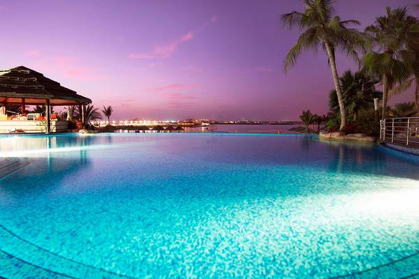 Le Meridien Mina Seyahi Beach Resort Pool bei Nacht mit Blick auf das Meer und Palmen