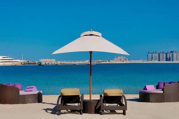 Strandszene mit Sonnenschirm und Liegen am Le Meridien Mina Seyahi Beach Resort & Waterpark