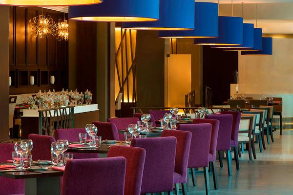 Restaurant des Le Meridien Mina Seyahi Beach Resort & Waterpark mit blauen Lampen und roten Stühlen.