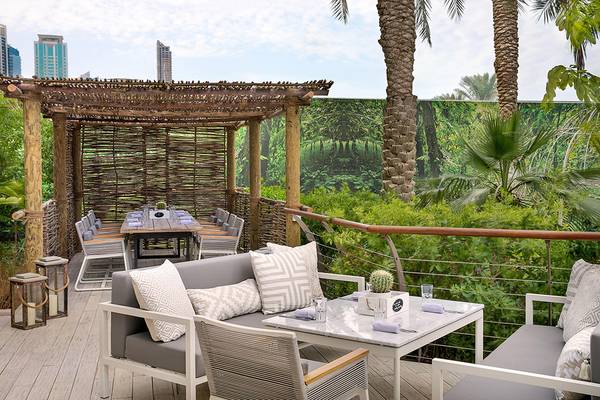 Terrasse im Le Meridien Mina Seyahi Beach Resort & Waterpark mit Möbeln und grünem Hintergrund