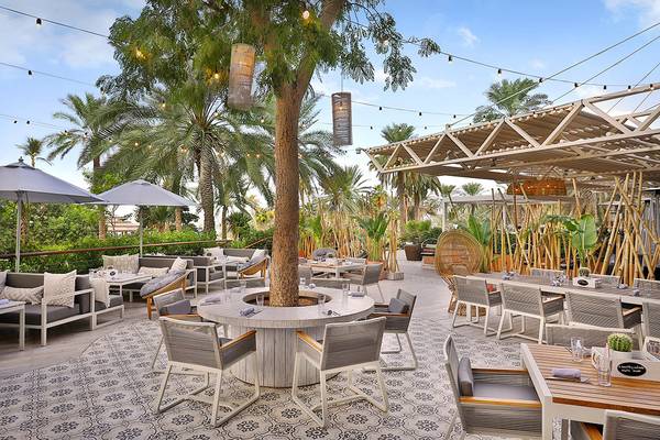 Außenterrasse des Le Meridien Mina Seyahi Beach Resort mit Tischen und Stühlen unter Pavillons