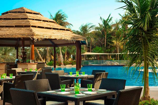 Außenbereich des Le Meridien Mina Seyahi Beach Resort mit Pool und Essbereichen.