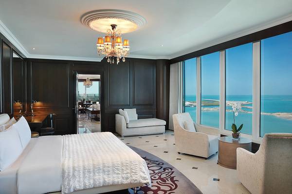 Luxuriöse Suite im Le Meridien Mina Seyahi Beach Resort mit Meerblick, Bett, Sofa und Aussichtsfenstern.