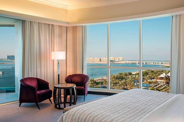 Zimmer im Le Meridien Mina Seyahi Beach Resort mit Meerblick und großer Fensterfront.