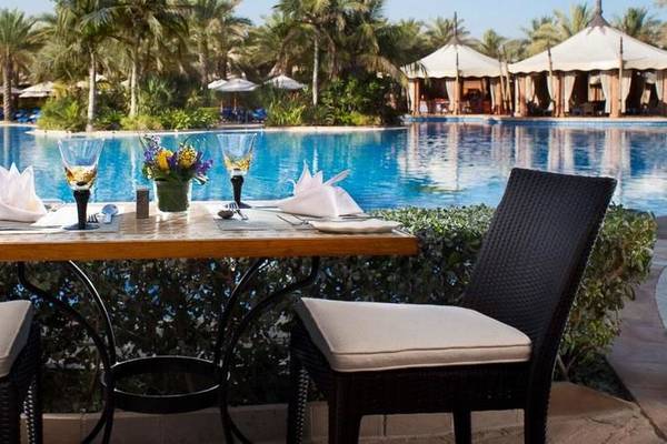 Außentisch am Pool des Jumeirah Al Qasr Hotels mit Blumen und Gläsern