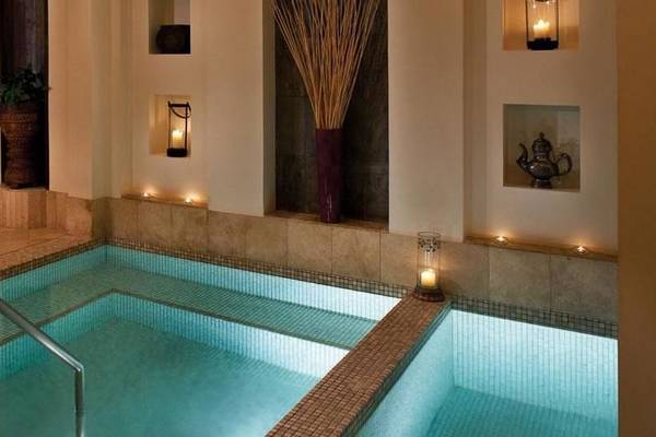 Innenpool des Jumeirah Al Qasr Hotels mit braunem Rand und beleuchteten Kerzen.